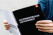 Eine Person hält das Schwarzweißbuch